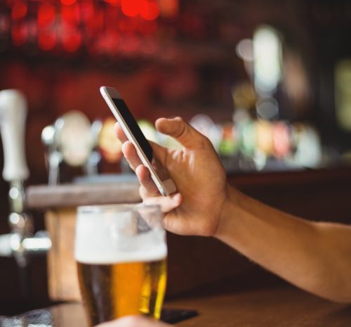 hombre-vaso-cerveza-telefono-movil-mostrador